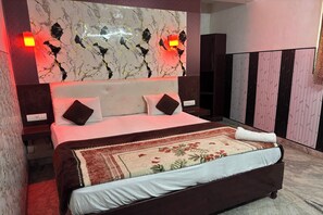 Un lit bien fait, avec une couvre-lit à motifs floraux, une tête de lit en marbre et deux lampes de chevet.