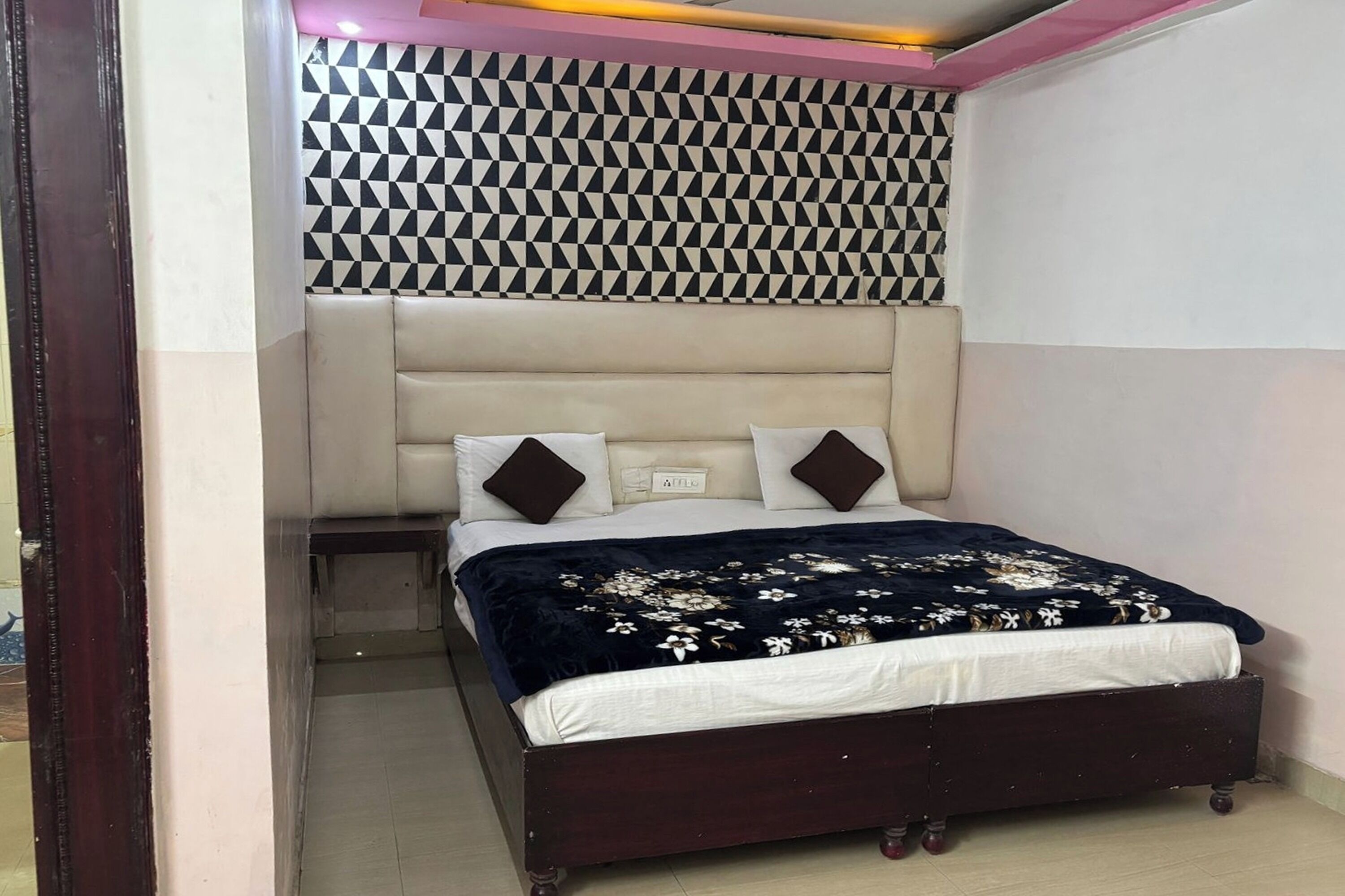 A bedroom with a bed, a headboard, and a patterned wall.