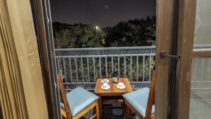 En balkon med et bord dækket til to, stole og udsigt til nattehimlen.