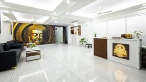 En moderne hotellobby med et Buddha-maleri, en receptionsdisk og et siddeområde med et sofabord.