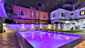 Ein Schwimmbecken mit Fliesen umrandet und einer Mauer mit integrierter Beleuchtung.