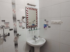 Ein Badezimmer mit einem weißen Waschbecken, einem Spiegel mit Streifenrahmen, einem Seifenspender und einem Händetrockner.