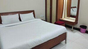 Una habitación de hotel con cama, armario, tocador con espejo y un cubo de basura.