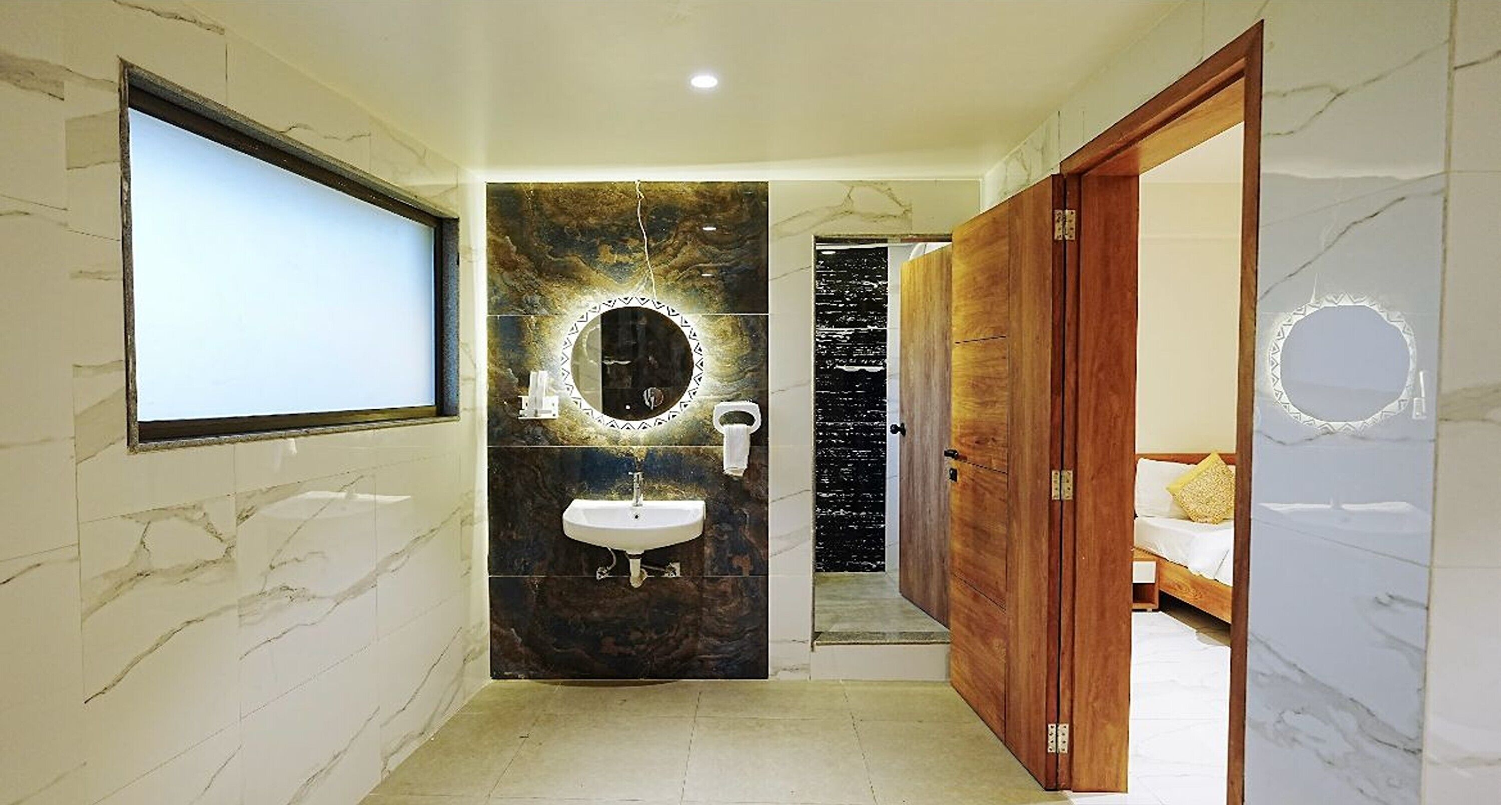 Un baño con pared de mármol, un lavamanos, un espejo y una puerta de madera.
