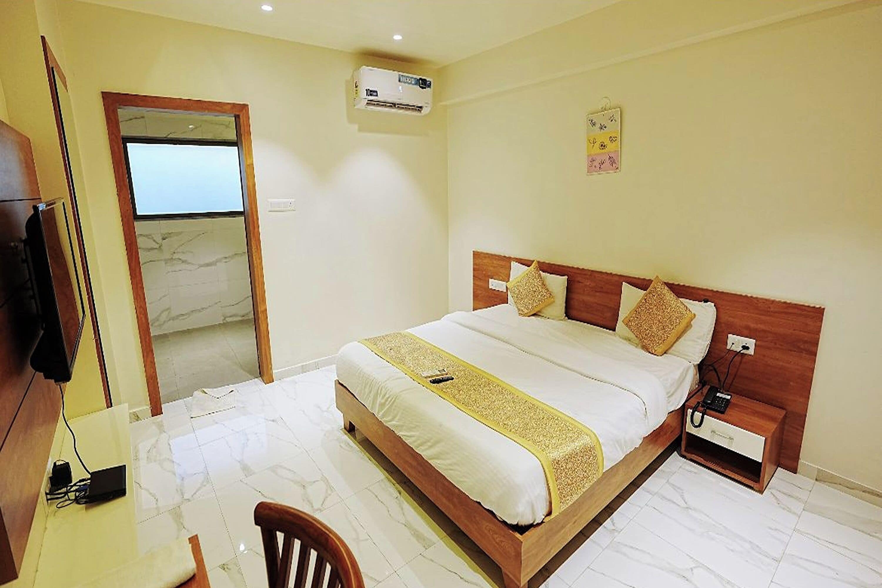 A hotel room with a bed, bedside table, and a TV.