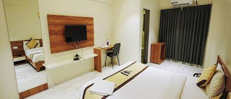 Habitación de hotel con una cama grande, un escritorio con silla, un televisor montado en la pared y un espejo amplio.