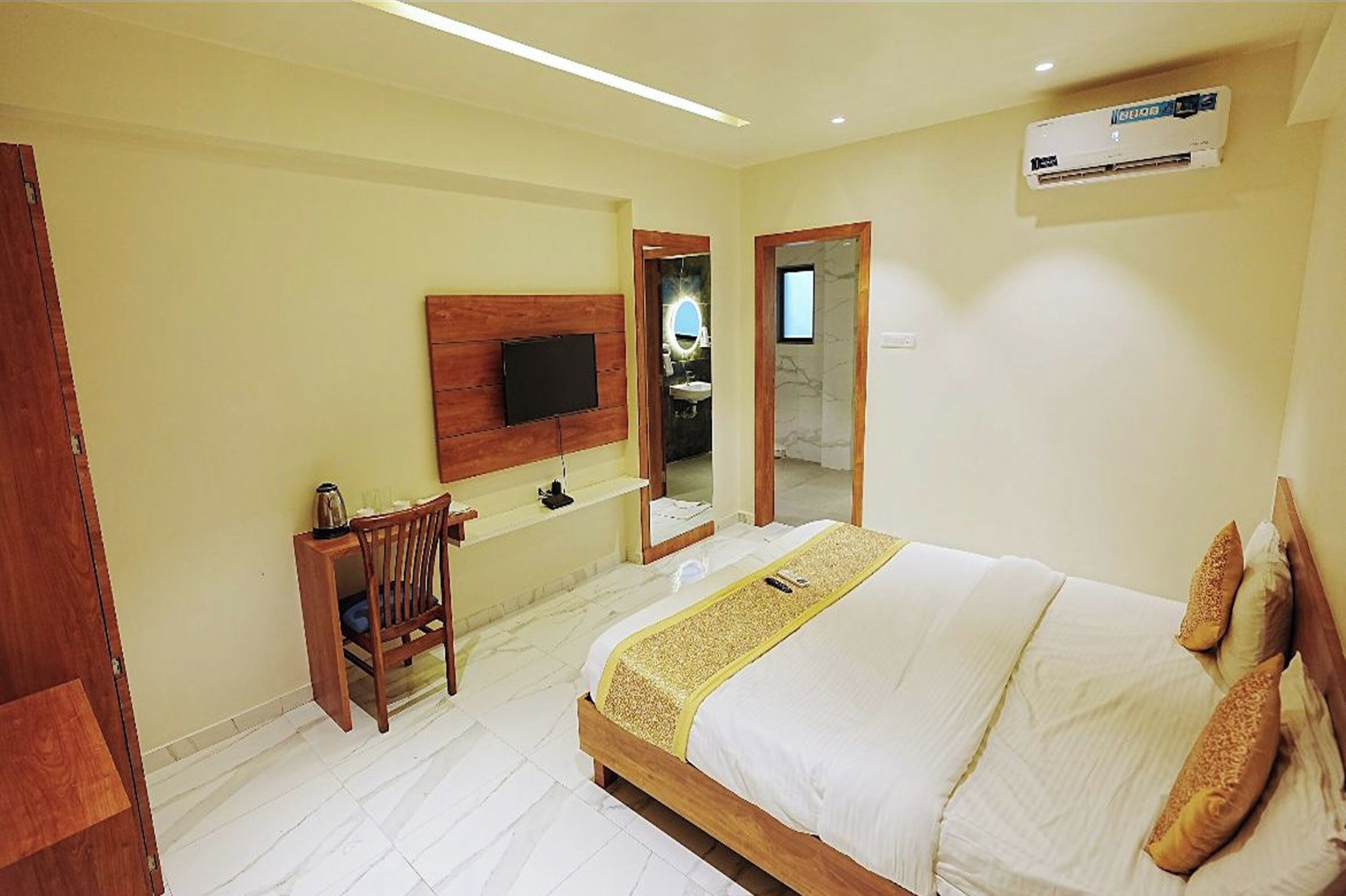 Une chambre d’hôtel avec un lit, un bureau, une chaise, une télévision et une salle de bain visible à travers une porte ouverte.