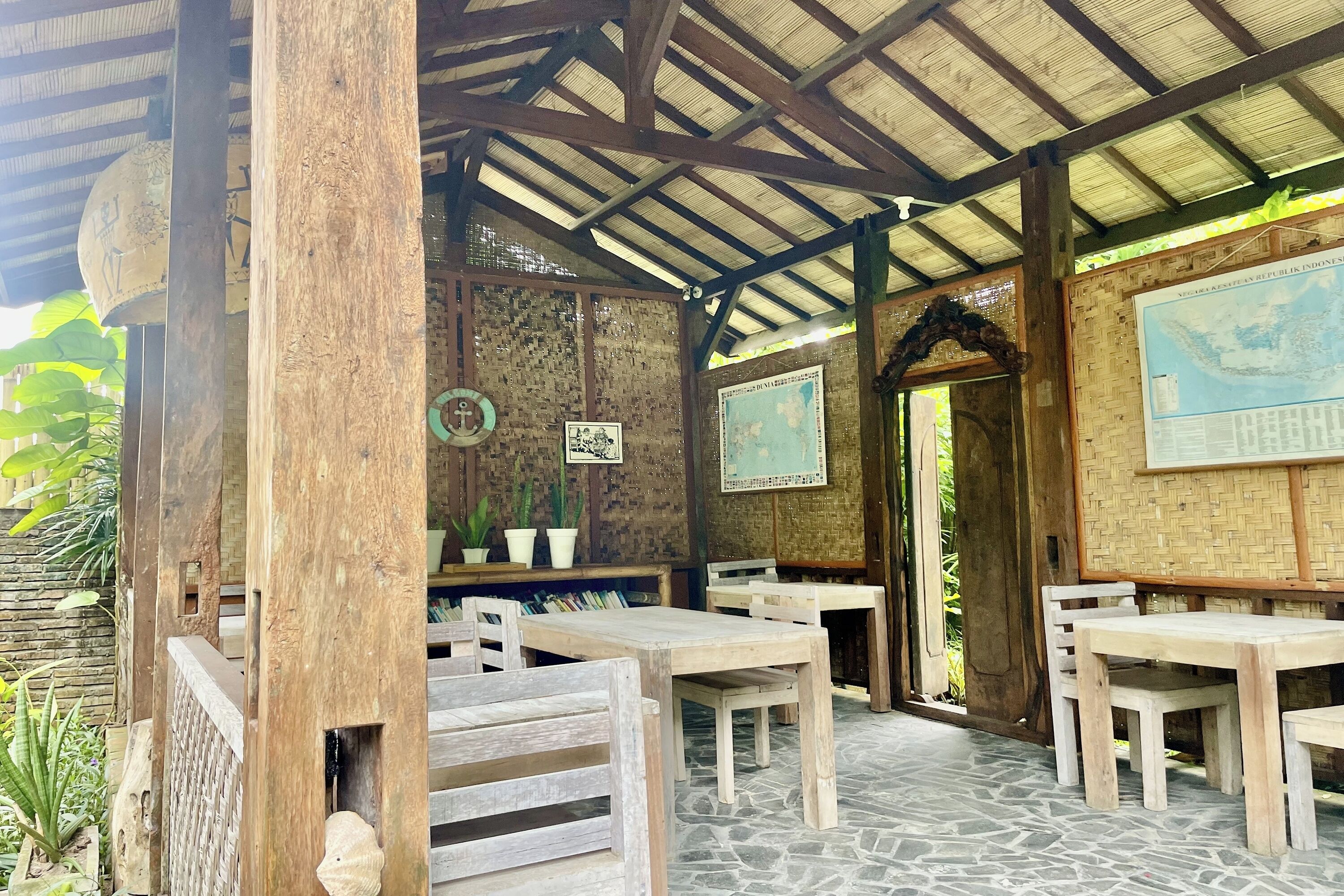 A rustic wooden structure with tables and chairs, a tiled floor, and a map on the wall.