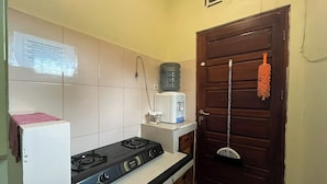 A kitchen with a gas stove, a microwave, and a water dispenser on the counter. - Jirek Homestay Bukittinggi (Bukittinggi)