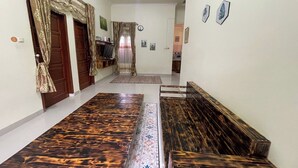 A hallway with patterned wooden flooring, wooden benches, and a door with curtains. - Jirek Homestay Bukittinggi (Bukittinggi)