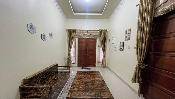 A hallway with a wooden bench, a patterned rug, and a door with curtains. - Jirek Homestay Bukittinggi (Bukittinggi)