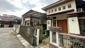 A residential building with a covered patio, a gated entrance, and a small garden area. - Jirek Homestay Bukittinggi (Bukittinggi)