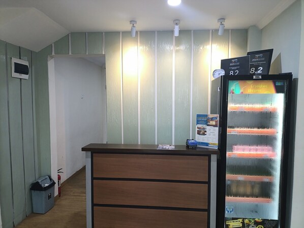Una reception con una sveglia digitale, un estintore e un cestino.