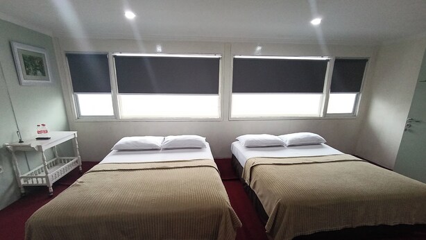 Ein Zimmer mit zwei Betten, einem kleinen Tisch und einem Fenster.