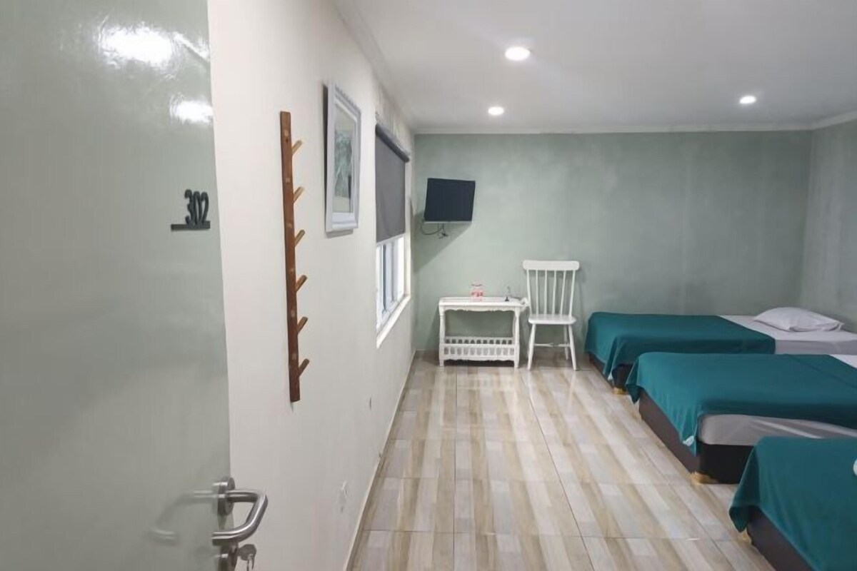 A room with two beds, a small table, a TV, and a window.