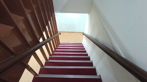 Eine Treppe mit roten Teppichstufen und Holzhandläufen.