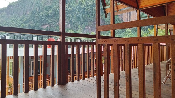 A wooden deck with a railing, overlooking a mountainous landscape. - Murai Pagi Homestay (Harau)