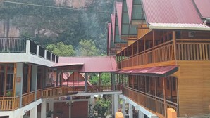 A multi-story building with balconies, wooden railings, and a red roof. - Murai Pagi Homestay (Harau)