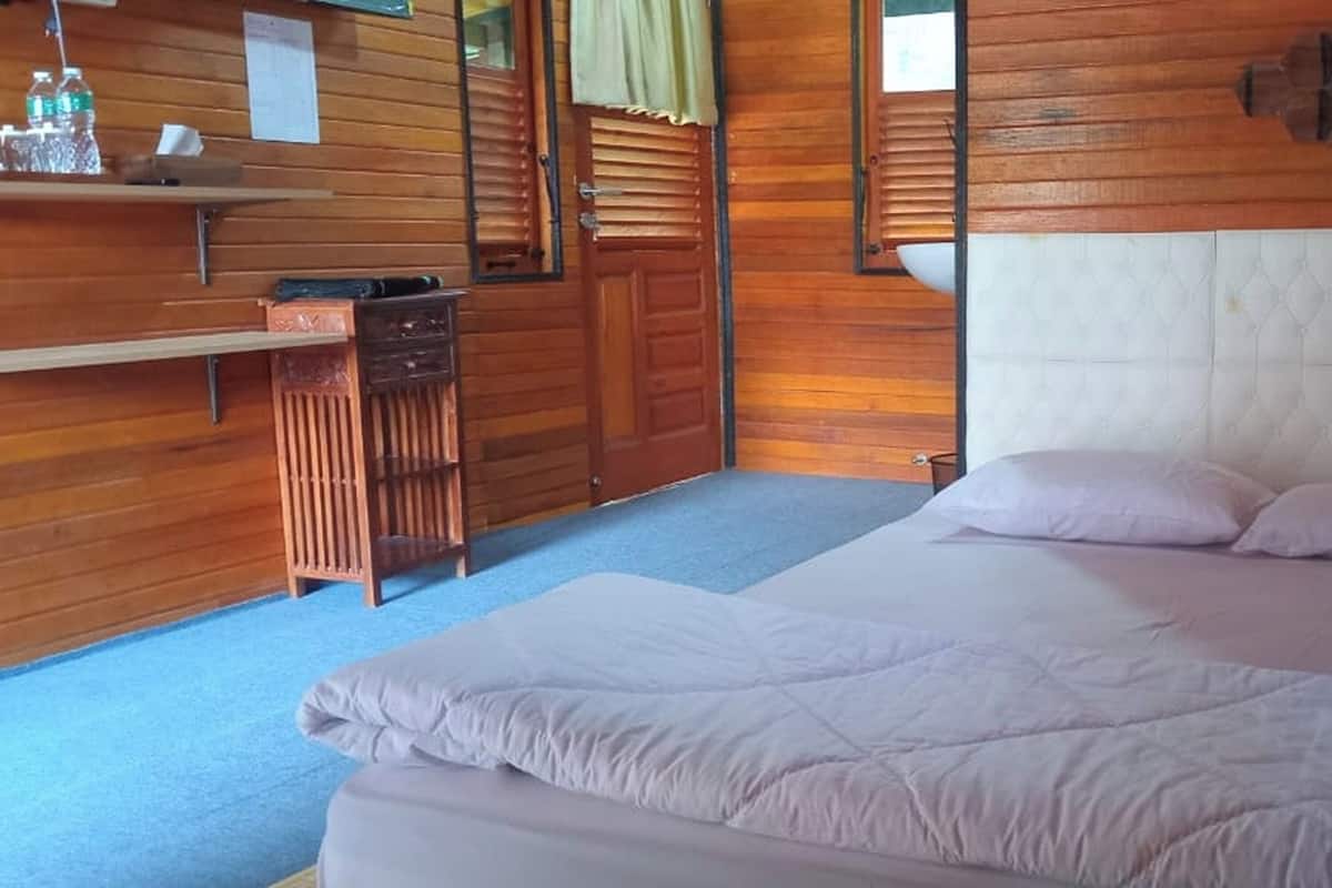 A wooden room with a bed, a small desk, and a mirror.