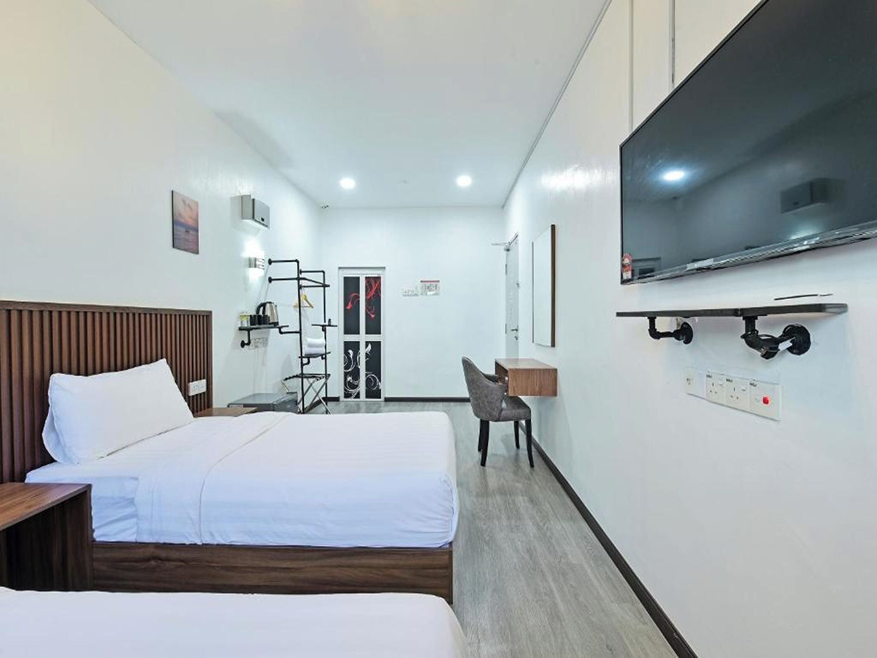 A hotel room with two beds, a TV, a desk, and a chair.