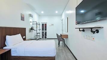 A hotel room with two beds, a TV, a desk, and a chair.