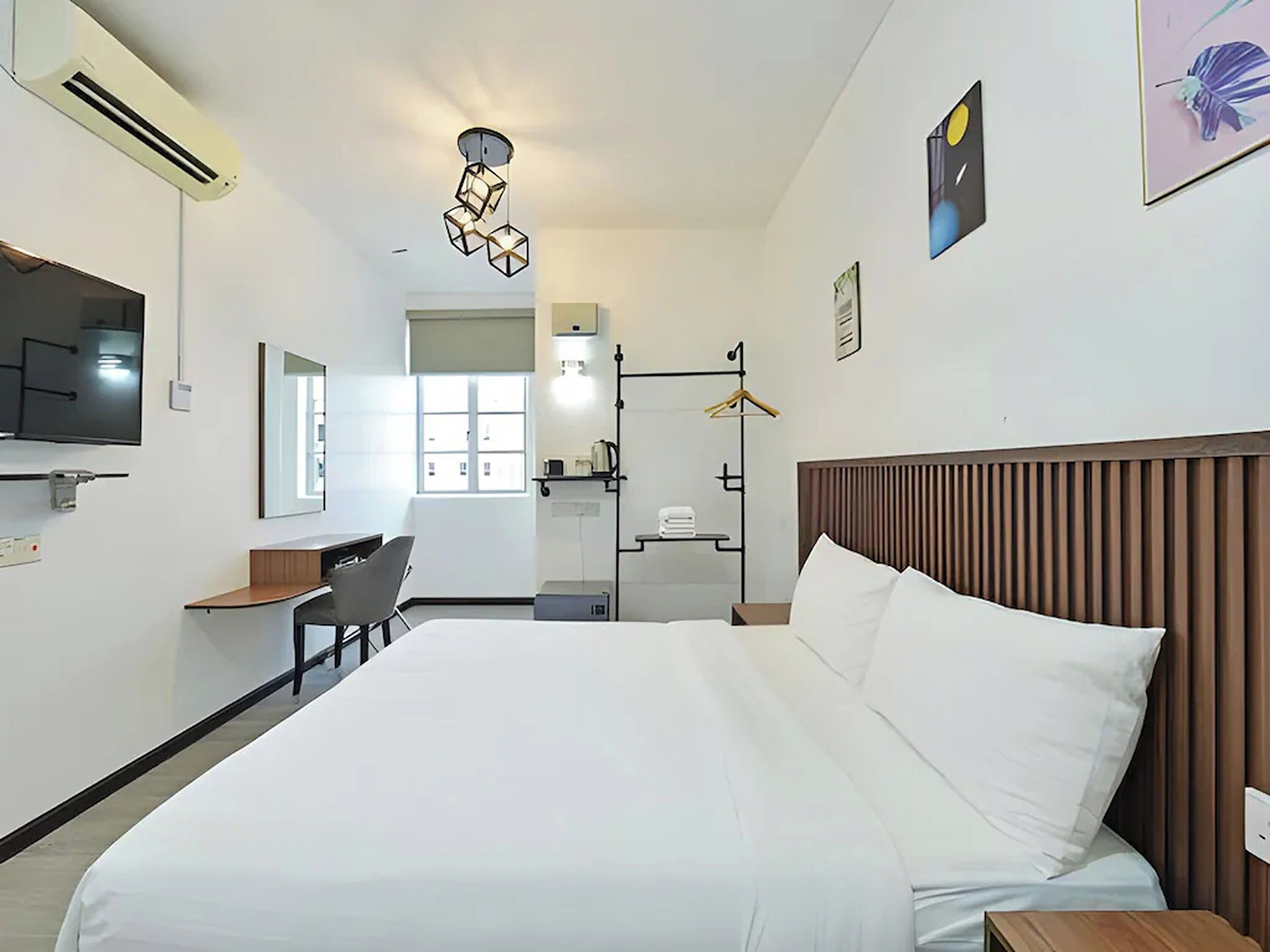 A hotel room with a bed, a desk, a chair, a TV, and a window.
