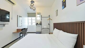 A hotel room with a bed, a desk, a chair, a TV, and a window.