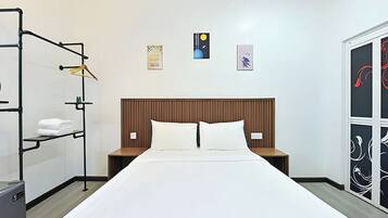 Una habitación de hotel con una cama, dos mesitas de noche, un armario y un estante con toallas.