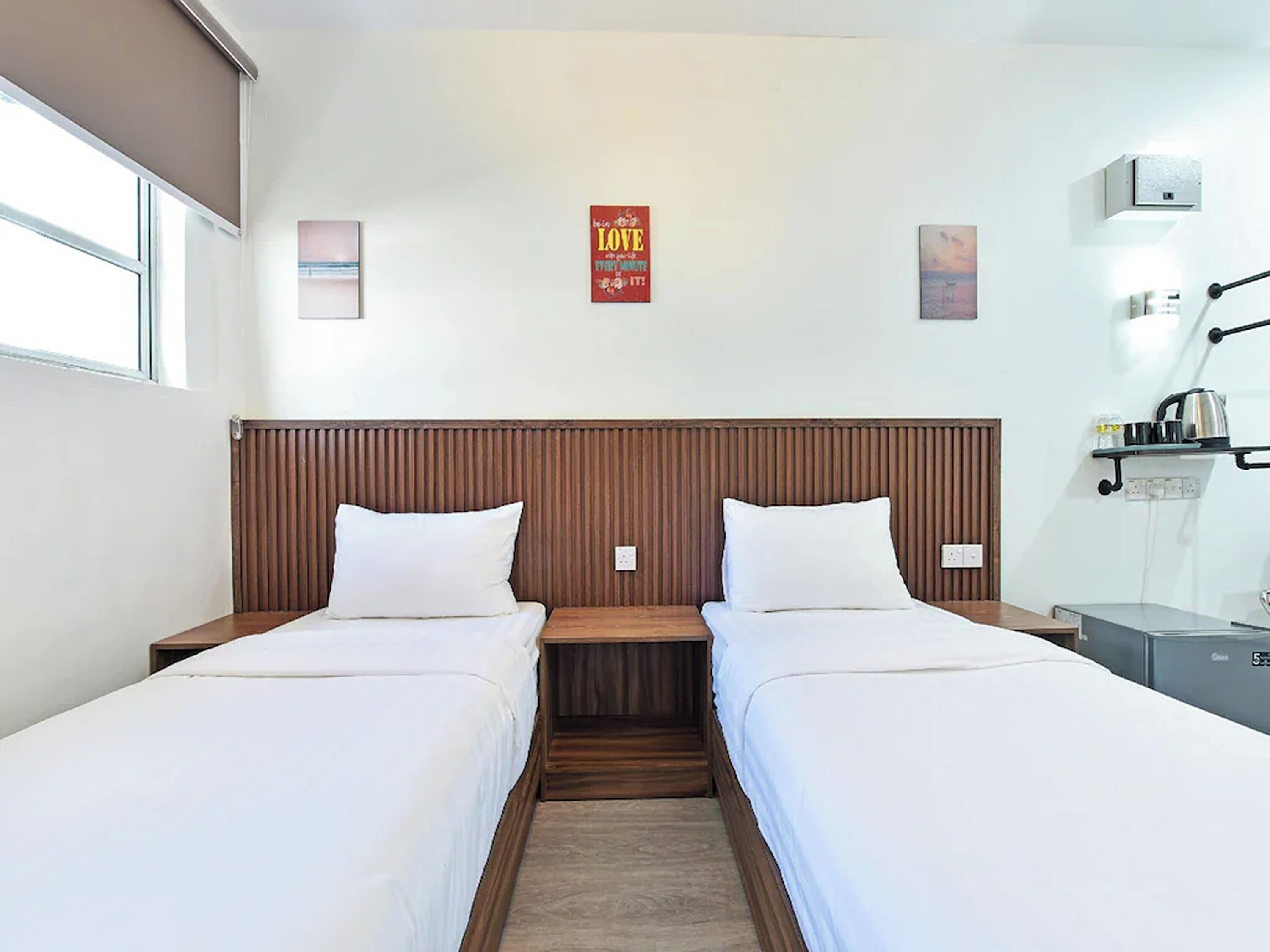 Una habitación de hotel con dos camas individuales, un cabecero de madera, una mesita y una mesita de noche.