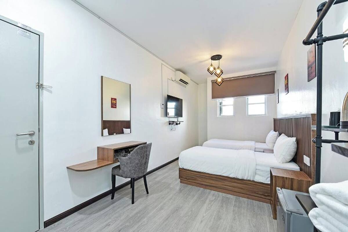 A modern hotel room with a bed, a desk, a chair, a TV, and a bathroom.