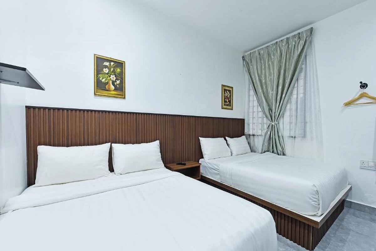 A hotel room with two beds, a wooden headboard, a nightstand, and a window with curtains.