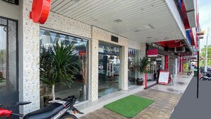 A storefront with a tiled facade, large windows, and potted plants. - Coop Hotel Kangar (Kangar)