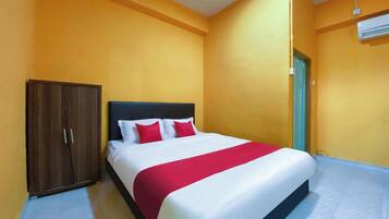 A hotel room with a bed, a wardrobe, and an air conditioning unit.