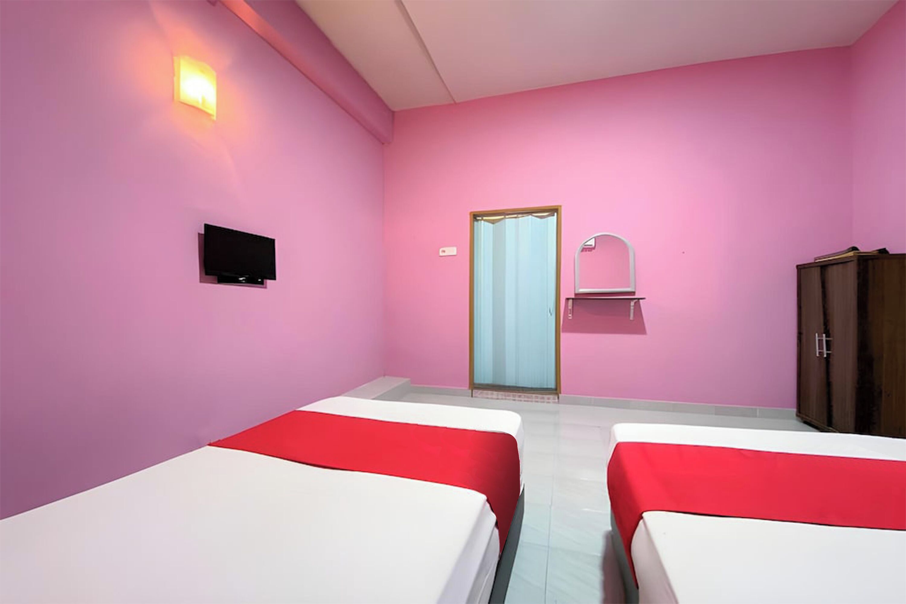 Ein Zimmer mit zwei Betten, einem Fernseher, einem Schrank und einem Spiegel.