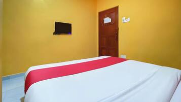 Habitación de hotel con cama, televisor montado en la pared y una puerta con un letrero.