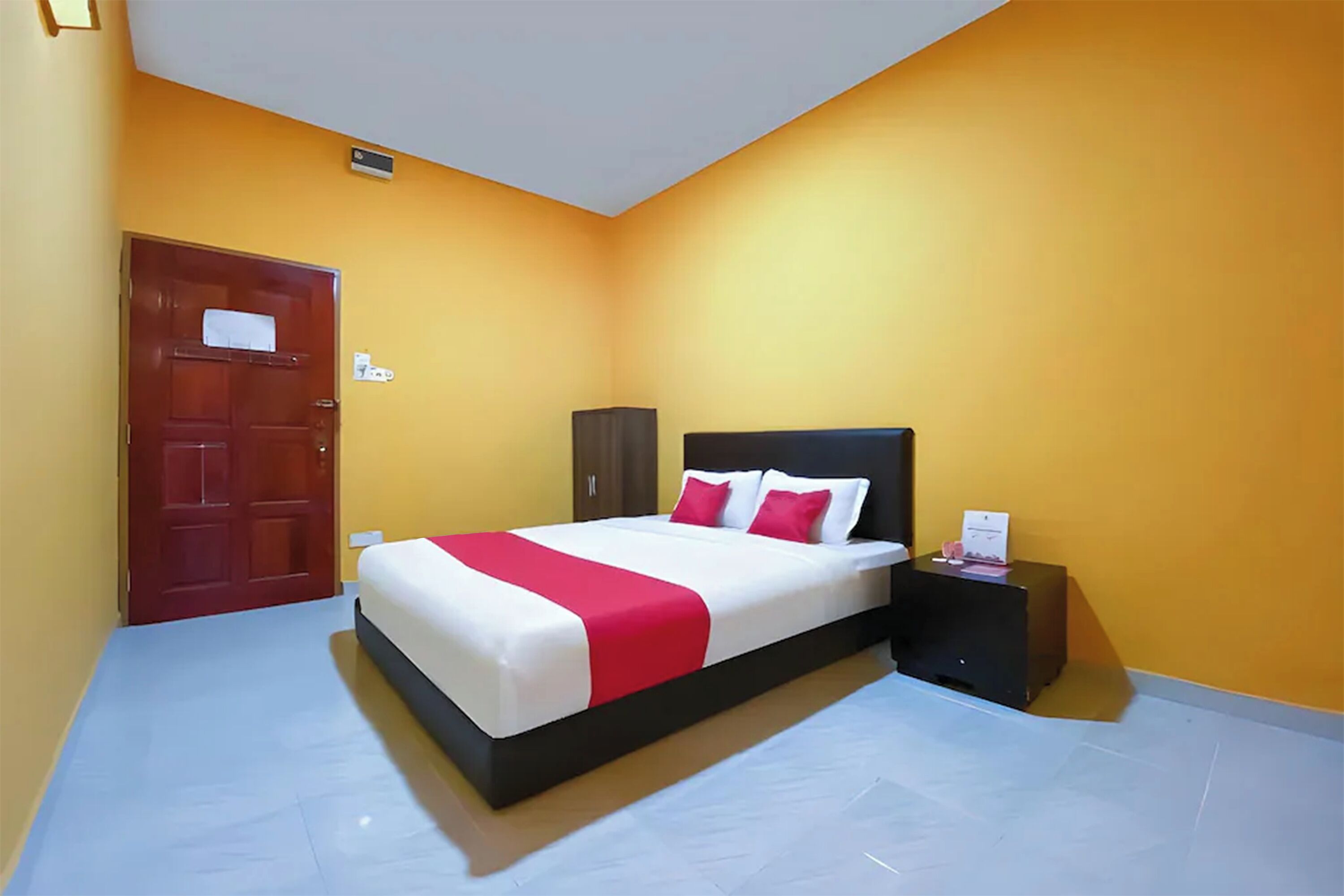 A bedroom with a bed, nightstand, and a door.
