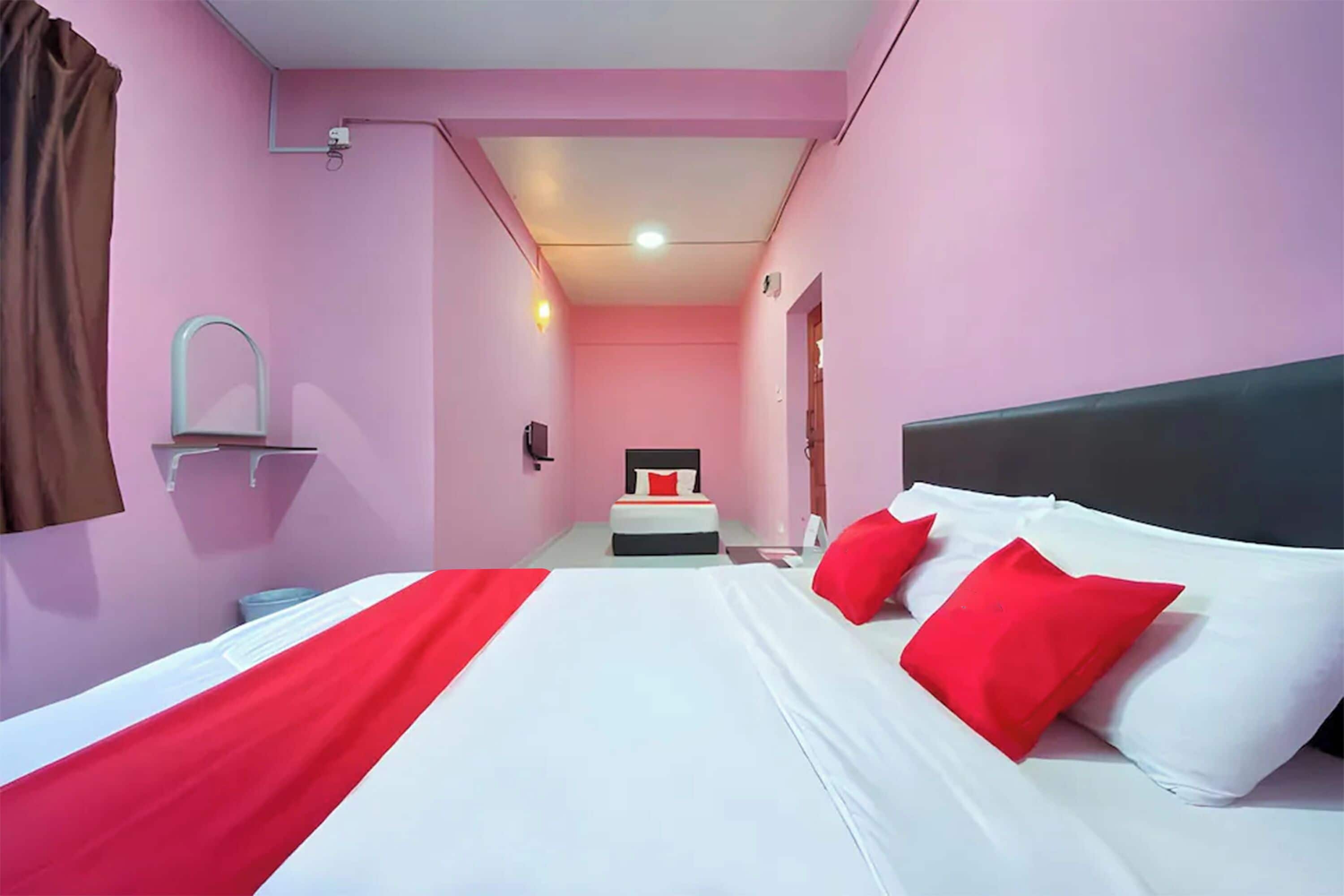 Una habitación de hotel con cama, mesita de noche, espejo y una pequeña mesa.