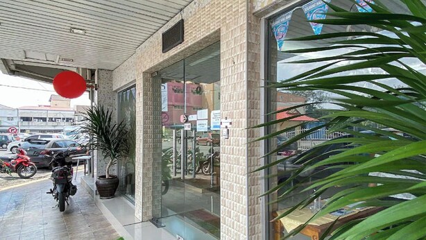A building with a glass entrance, a motorcycle parked outside, and a red balloon. - Coop Hotel Kangar (Kangar)