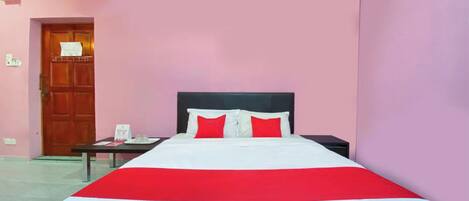 A hotel room with a bed, a nightstand, a wooden door, and a wall-mounted air conditioner.