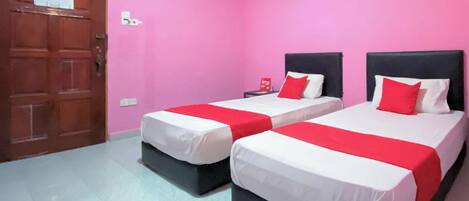 A room with two beds, pink walls, and a wooden door.