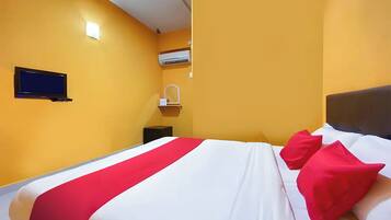 Habitación de hotel con cama, televisor montado en la pared, aire acondicionado y una mesita de noche.