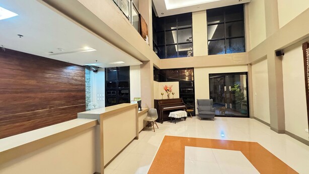 A spacious lobby with a reception desk, a piano, seating area, and large windows. - Hotel Ramon Bukidnon (Valencia)