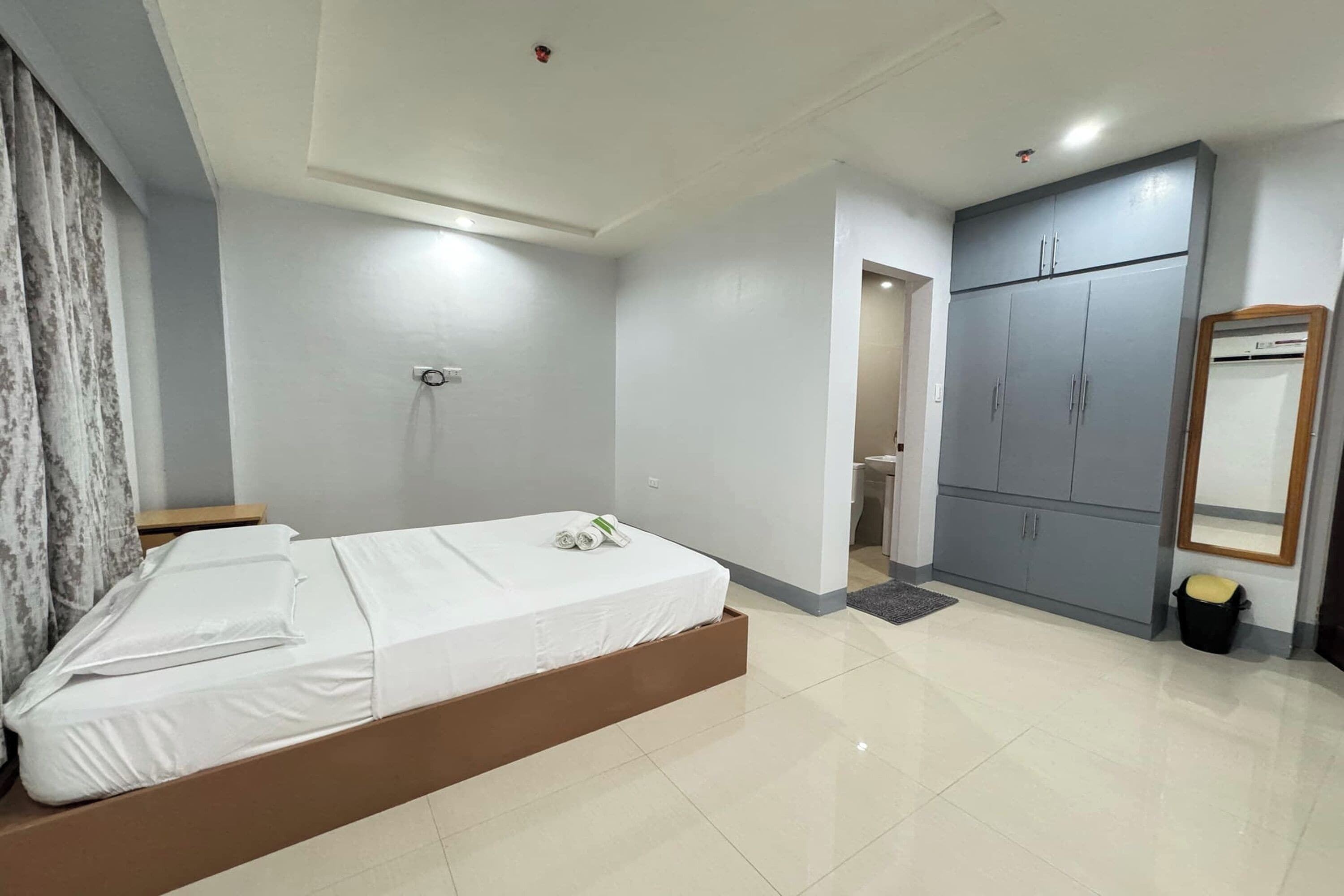 A modern bedroom with a bed, wardrobe, and a bathroom visible through an open door.