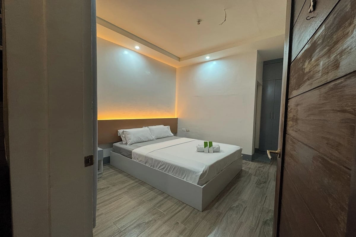 Ein modernes Schlafzimmer mit einem großen Bett, einem Nachttisch und einer Wandleuchte.