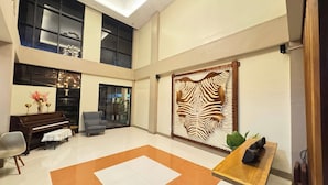 A spacious lobby with a piano, seating area, and a decorative wall. - Hotel Ramon Bukidnon (Valencia)
