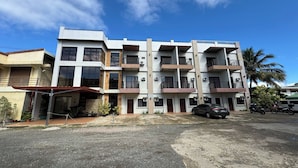 A multi-story residential building with balconies, a covered entrance, and a parking area. - Hotel Ramon Bukidnon (Valencia)