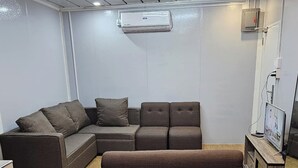 A modern living room with a sectional sofa, a single couch, and a TV stand. - Tres Marias Farmhouse with Pool (Cuyapo)
