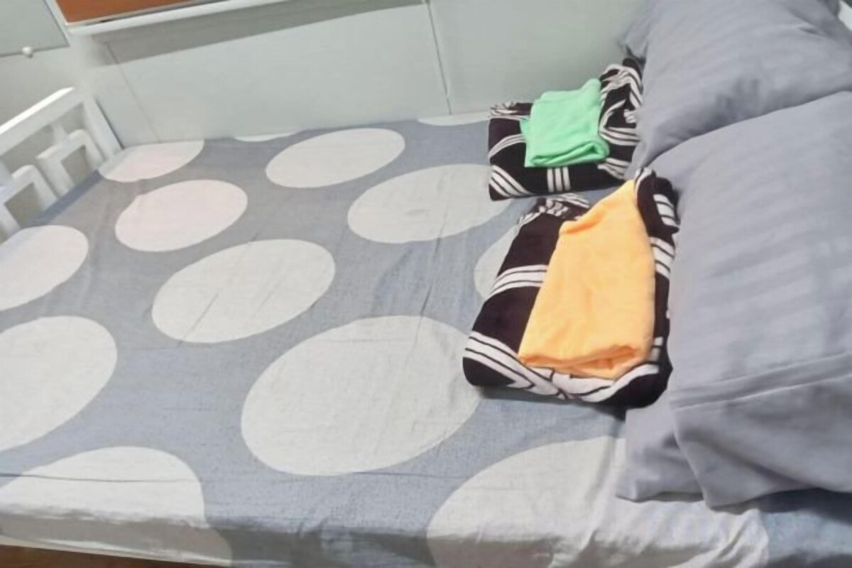 A bed with a polka dot bedspread, pillows, and folded clothes.