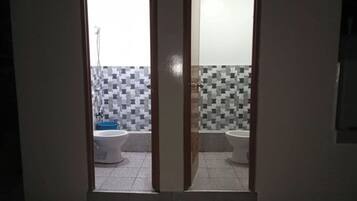 Un baño con suelo de baldosas, un lavabo blanco y un inodoro.