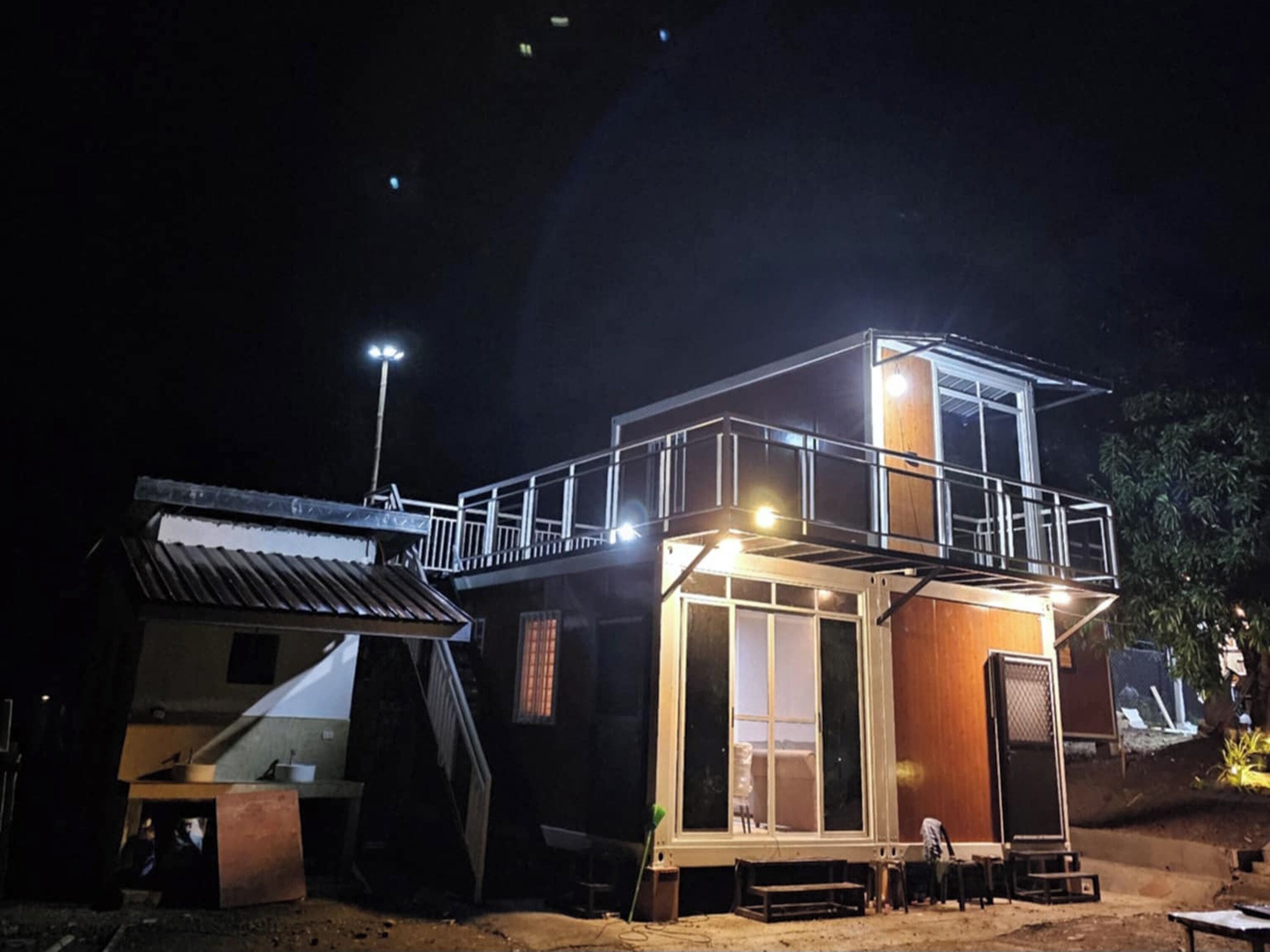 Un bâtiment à deux étages doté d’un balcon, d’une petite dépendance attenante et d’une zone pavée devant l’entrée.